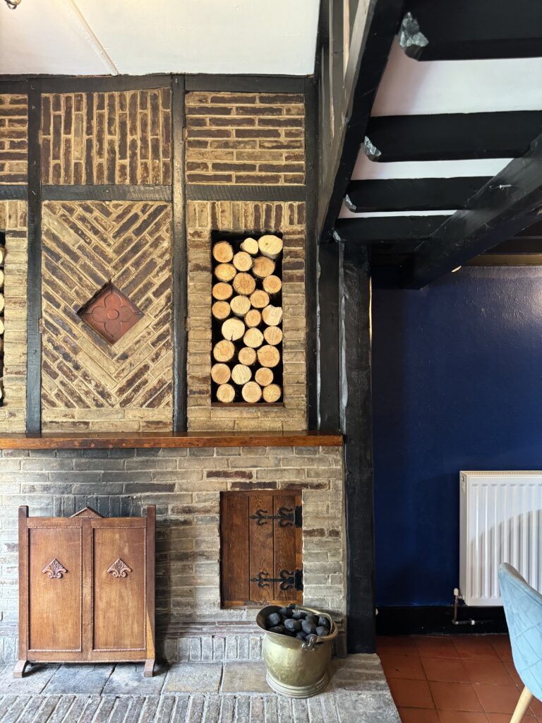 Logs sitting upon the lounge bar fireplace for a cosy effect